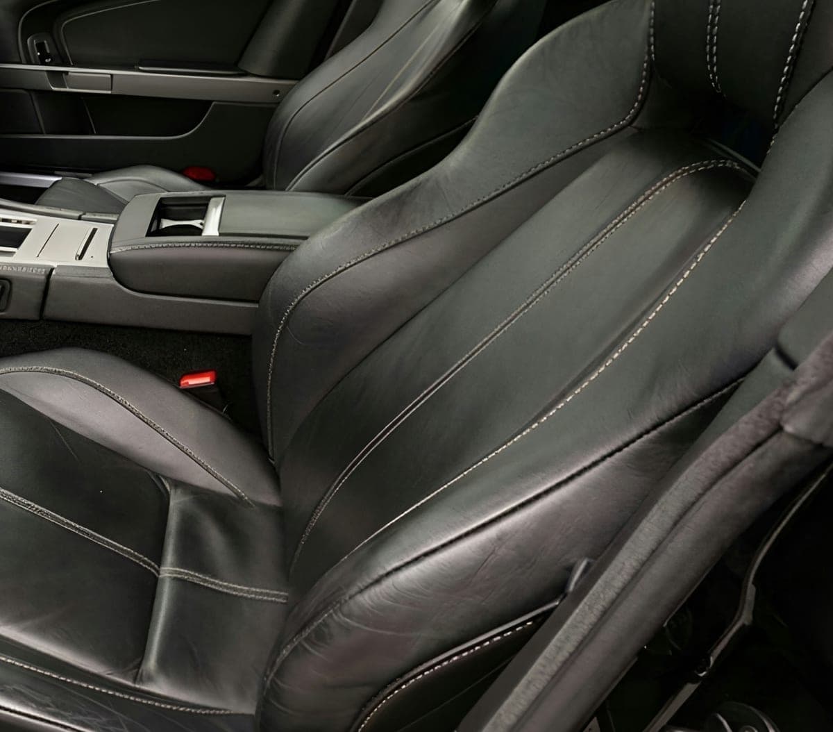 Hand-finished stitching across dark leather sport seats.