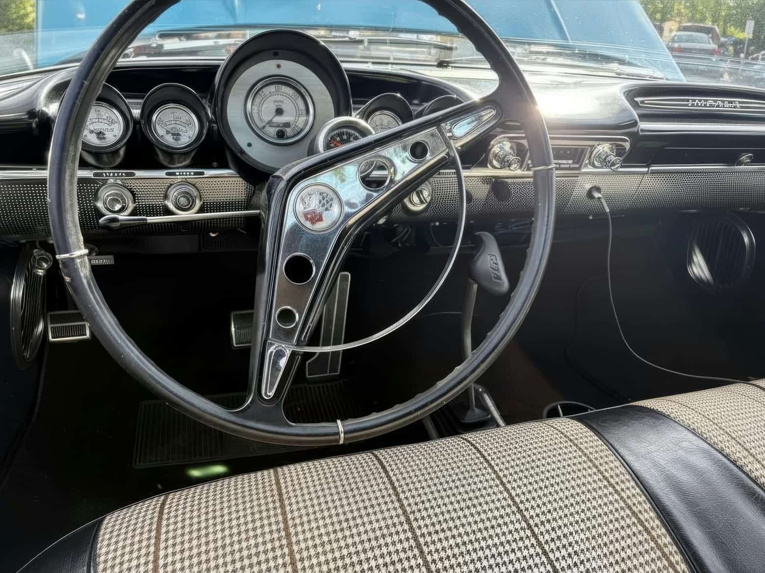 A vintage dashboard's chrome gauges and houndstooth bench, kept bright after decades of use.
